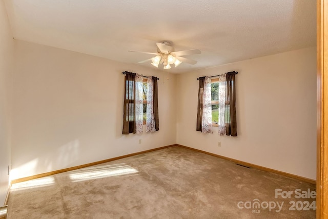 carpeted empty room with ceiling fan and a textured ceiling