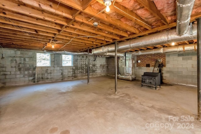 basement featuring heating unit and a wood stove