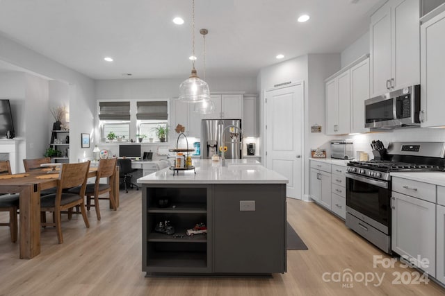 kitchen featuring white cabinetry, an island with sink, pendant lighting, appliances with stainless steel finishes, and light wood-type flooring