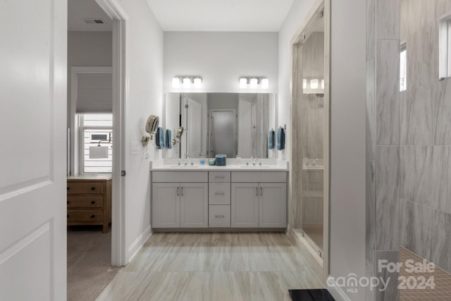 bathroom with vanity, a tile shower, and a wealth of natural light