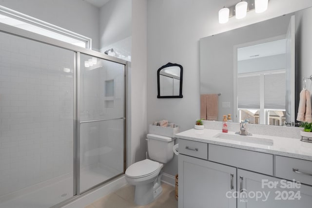 bathroom with tile patterned flooring, vanity, toilet, and a shower with door