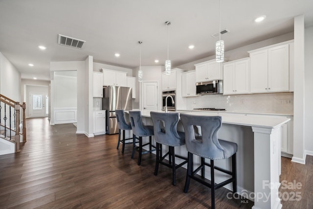 kitchen with pendant lighting, a spacious island, white cabinetry, and appliances with stainless steel finishes