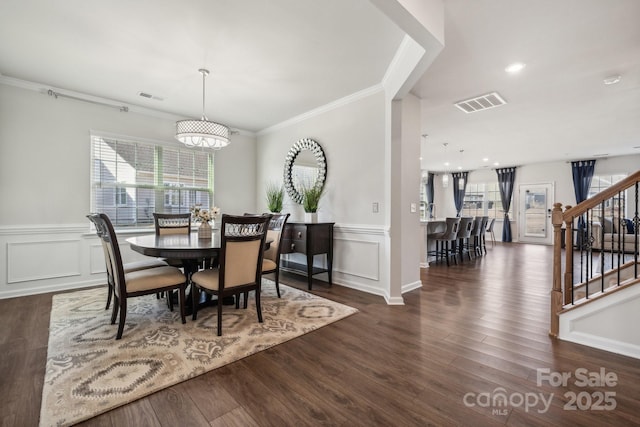 dining room with ornamental molding, an inviting chandelier, and dark wood-type flooring