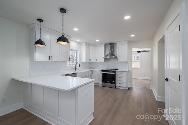 kitchen featuring hanging light fixtures, white cabinets, stainless steel electric range oven, kitchen peninsula, and wall chimney exhaust hood