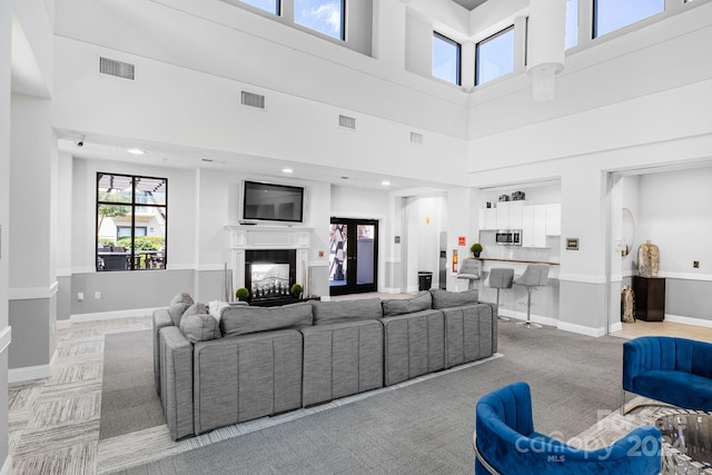 living room with a towering ceiling and carpet floors