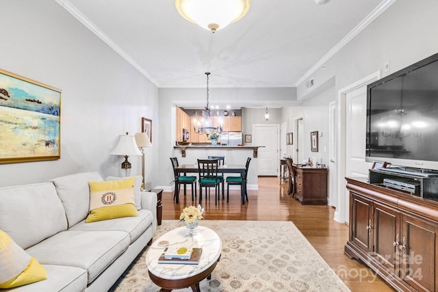 living room with a chandelier, wood-type flooring, and ornamental molding