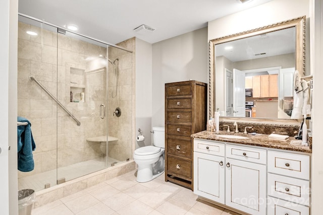 bathroom featuring tile patterned floors, vanity, a shower with shower door, and toilet