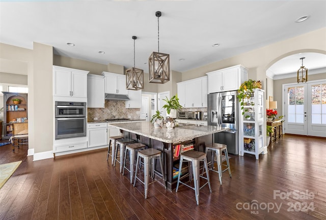 kitchen featuring a center island with sink, dark hardwood / wood-style floors, white cabinets, and appliances with stainless steel finishes