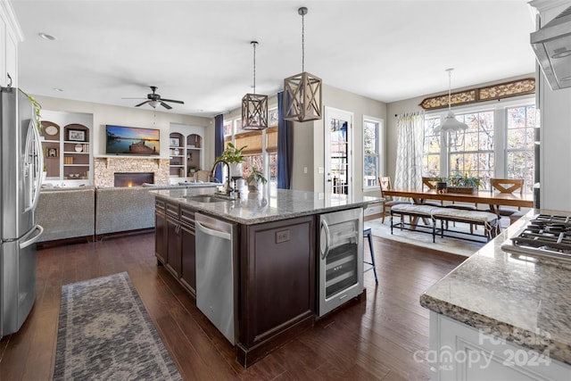 kitchen featuring appliances with stainless steel finishes, dark brown cabinetry, dark wood-type flooring, wine cooler, and hanging light fixtures