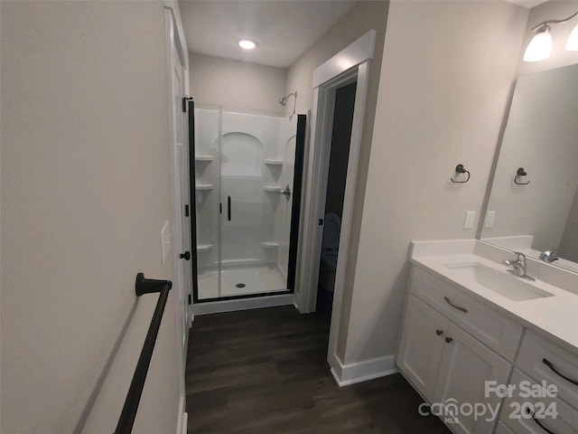 bathroom with hardwood / wood-style floors, vanity, and a shower with door