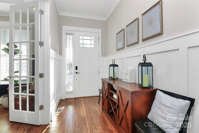 foyer entrance with a wainscoted wall, visible vents, wood finished floors, and ornamental molding