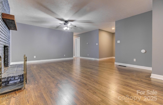 unfurnished living room with ceiling fan, a textured ceiling, dark hardwood / wood-style floors, and a fireplace