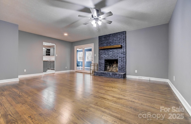 unfurnished living room featuring ceiling fan, a brick fireplace, a textured ceiling, and hardwood / wood-style floors