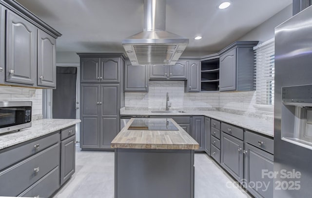 kitchen featuring a center island, sink, island exhaust hood, gray cabinetry, and stainless steel appliances