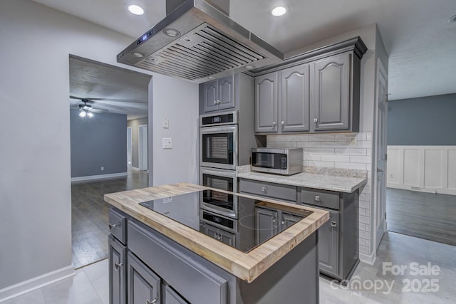 kitchen with a kitchen island, butcher block counters, island range hood, and gray cabinets