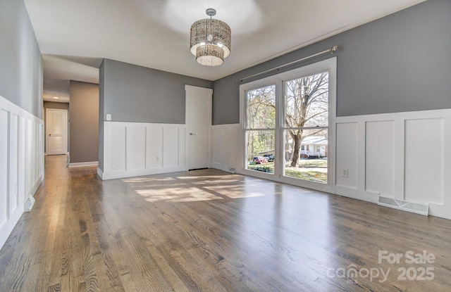 unfurnished room with an inviting chandelier and wood-type flooring