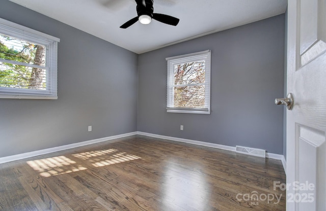 unfurnished room featuring ceiling fan, dark wood-type flooring, and a healthy amount of sunlight