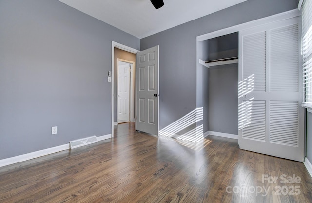 unfurnished bedroom with ceiling fan, a closet, and dark hardwood / wood-style flooring