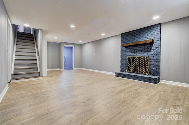 basement featuring a brick fireplace and light hardwood / wood-style floors