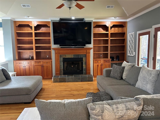 living room with ceiling fan, ornamental molding, a fireplace, and light hardwood / wood-style flooring