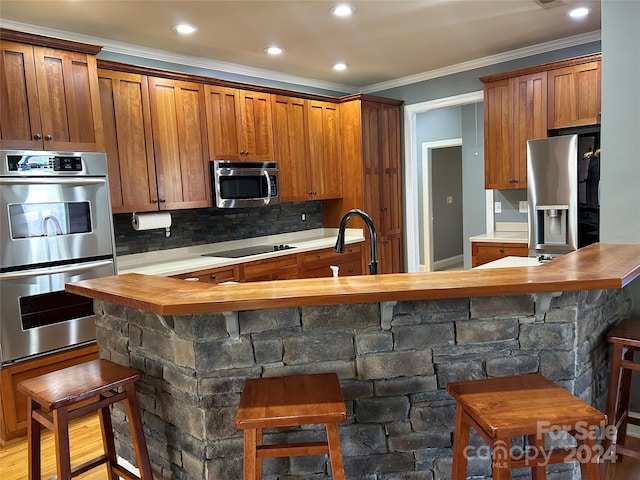 kitchen featuring a breakfast bar area, hardwood / wood-style floors, stainless steel appliances, and wood counters