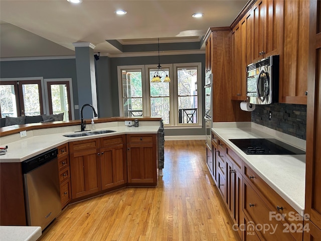 kitchen with appliances with stainless steel finishes, light wood-type flooring, sink, a chandelier, and hanging light fixtures