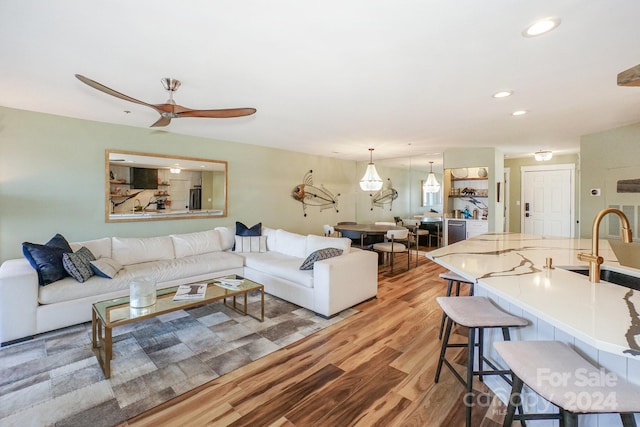 living room with ceiling fan, light wood-type flooring, and sink