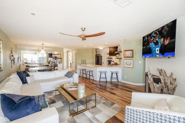 living area with visible vents, baseboards, ceiling fan, and wood finished floors