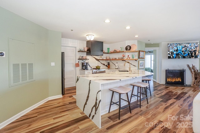 kitchen featuring open shelves, visible vents, a breakfast bar, and light wood-style floors