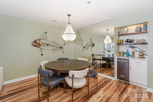 dining area with baseboards, a notable chandelier, light wood-style flooring, and visible vents