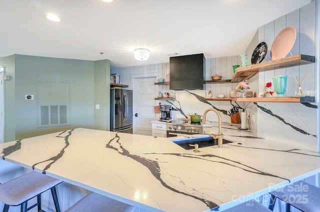 kitchen with open shelves, freestanding refrigerator, and light stone countertops