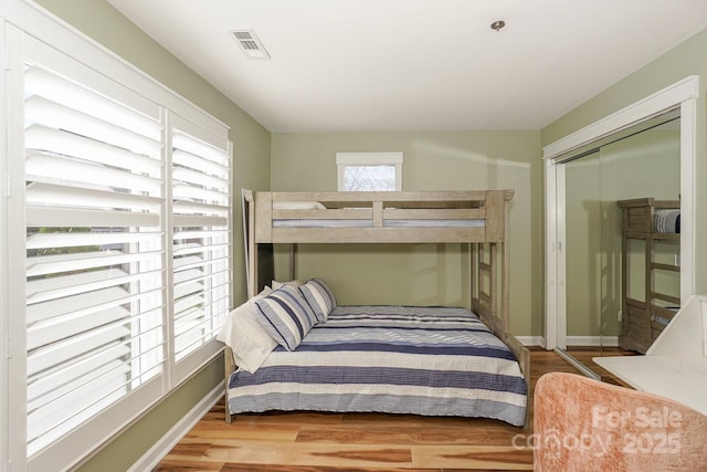 bedroom featuring visible vents, baseboards, wood finished floors, and a closet