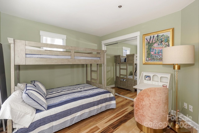 bedroom featuring baseboards, multiple windows, wood finished floors, and a closet