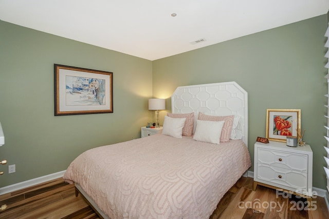 bedroom featuring baseboards, wood finished floors, and visible vents