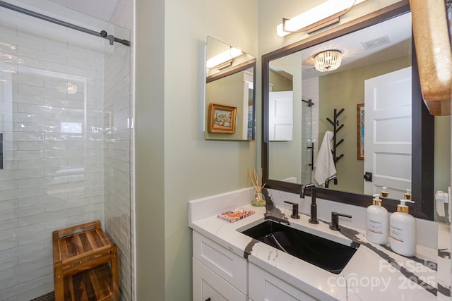 bathroom featuring visible vents, vanity, and tiled shower