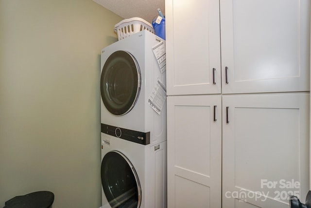 laundry area with stacked washer and clothes dryer and cabinet space
