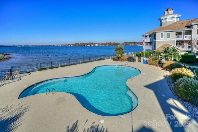 pool with a water view, fence, and a patio area