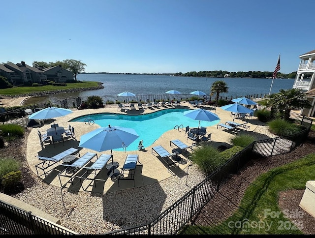 pool with a water view, fence, and a patio area