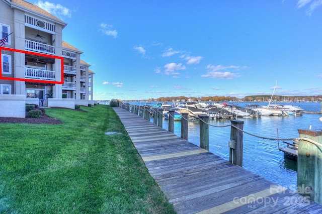 view of dock with a yard and a water view