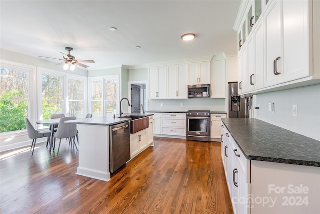 kitchen with a kitchen island with sink, ceiling fan, dark hardwood / wood-style floors, white cabinetry, and stainless steel appliances