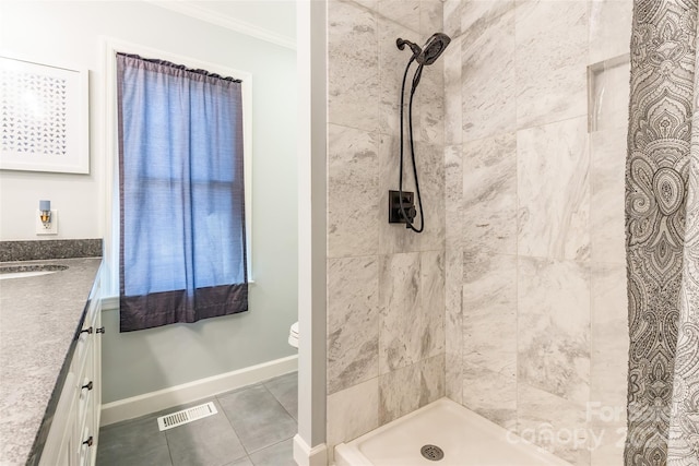 bathroom featuring tile patterned flooring, crown molding, toilet, tiled shower, and vanity