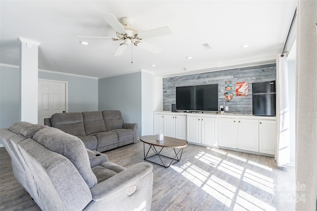 living room with light hardwood / wood-style floors, ceiling fan, and ornamental molding