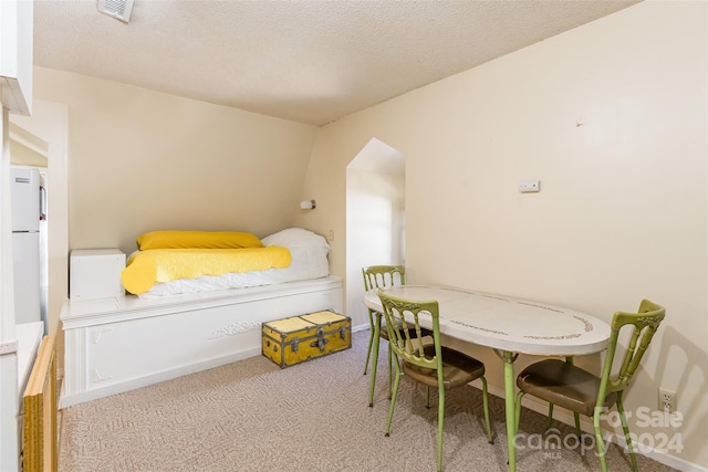 carpeted bedroom featuring a textured ceiling and white fridge