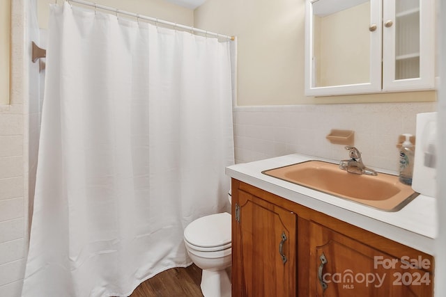 bathroom with wood-type flooring, vanity, toilet, and tile walls