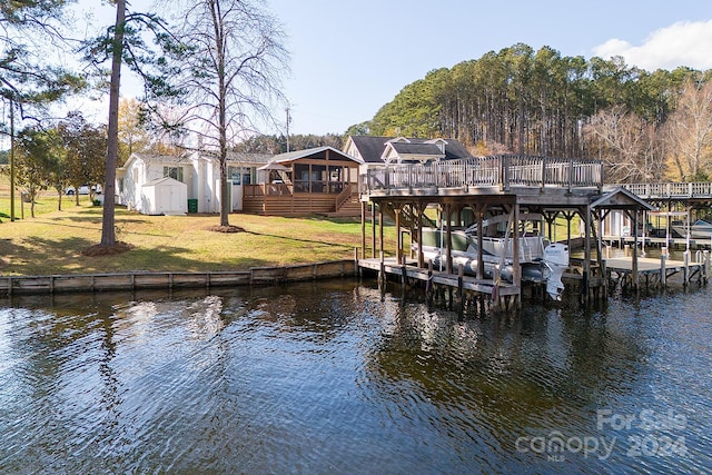 view of dock with a lawn and a water view