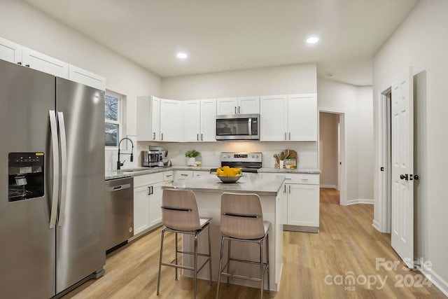 kitchen with white cabinets, appliances with stainless steel finishes, a center island, and sink
