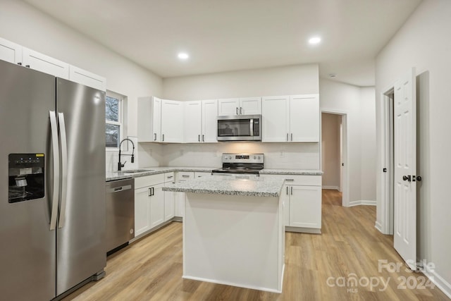 kitchen featuring white cabinets, stainless steel appliances, a kitchen island, and sink