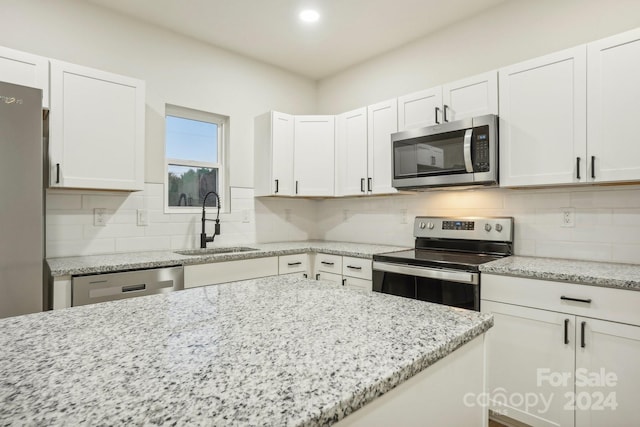 kitchen featuring white cabinetry, sink, light stone countertops, decorative backsplash, and appliances with stainless steel finishes