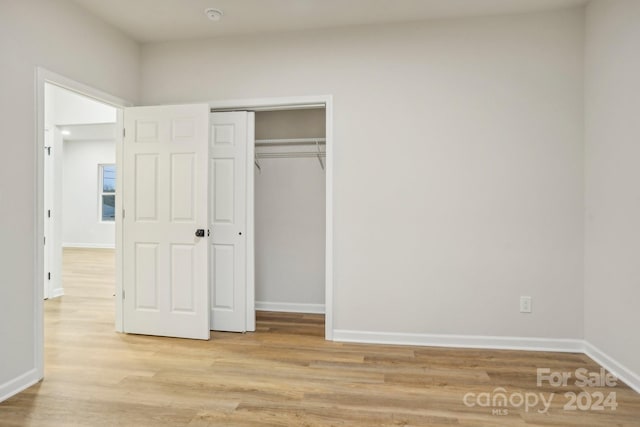 unfurnished bedroom with a closet and light hardwood / wood-style floors