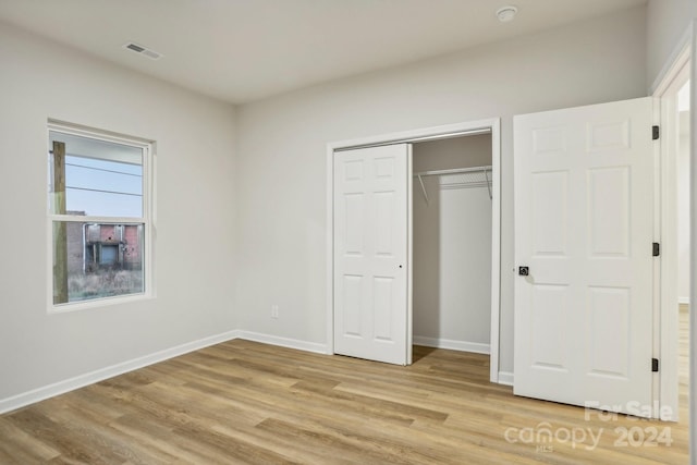 unfurnished bedroom featuring light wood-type flooring and a closet